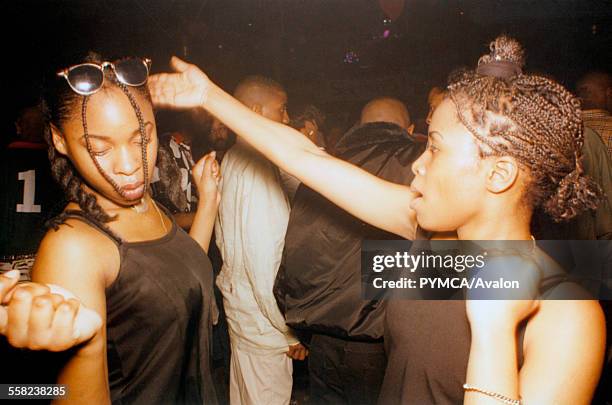 Two girls dancing, trying to clip the other round the back of the head, Voodoo Magic, The Empire, London, 1995.