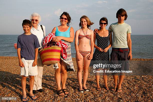 Women and children pose for family snap on a summer beach early evening light , Suffolk coast, England