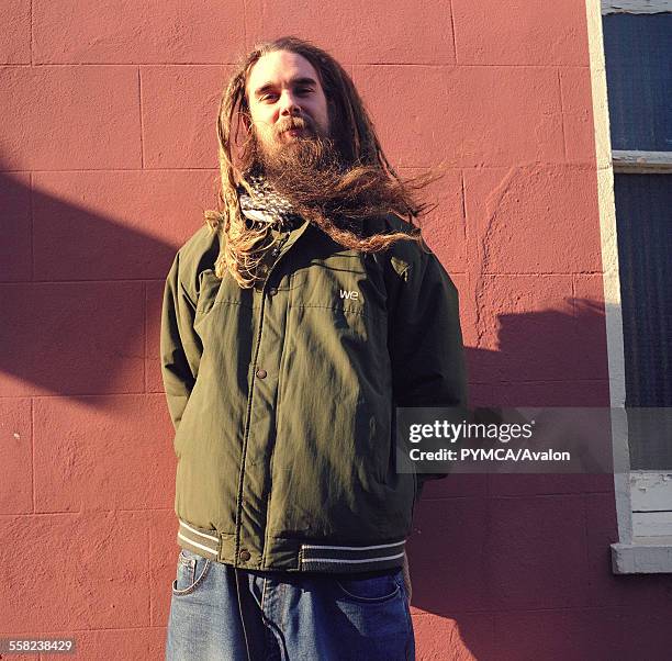 Hippy man with a long beard and a dreadlocks standing against a wall, Shoreditch, London, 2002.