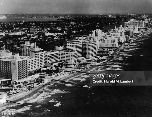 Aerial view looking North which shows the oceanfront luxury resort hotels of Miami Beach, Florida, 1950s or 1960s. Prominant buildings include the...