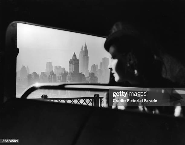 Female passenger on a bus which travels over the 59th Street Bridge to Queens looks out South onto the hazy New York City midtown skyline, New York,...