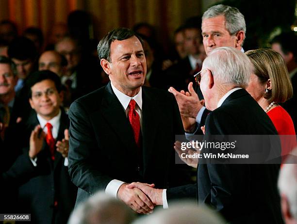 Supreme Court Chief Justice John Roberts shakes hands with Associate Justice John Paul Stevens after being sworn in during a ceremony in the East...