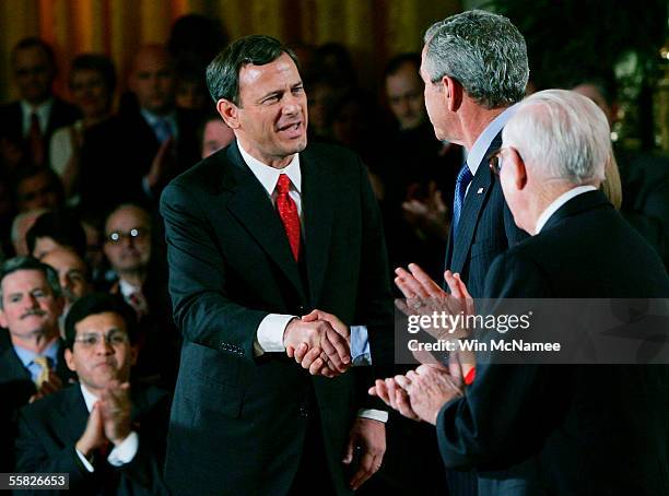Supreme Court Chief Justice John Roberts shakes hands with U.S. President George W. Bush as U.S. Supreme Court Associate Justice John Paul Stevens...