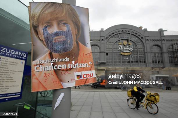 Postal worker cycles past a defaced poster featuring Christian Democratic Union leader Angela Merkel in front of Dresden?s main railway station 30...