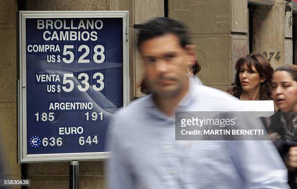 Transeuntes pasan junto a la pizarra de un cambio que indica el valor del dolar, en el centro de Santiago, el 30 de septiembre de 2005. El peso...