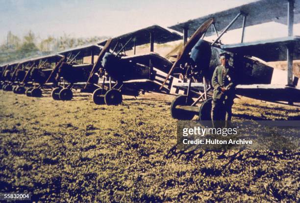 German soldier stands near a row of Fokker DR-1 tri-planes on an airfield, Germany, 1910s. The DR-1 was designed by aircraft manufacturer Anthony...