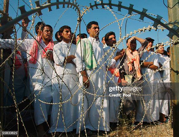 Detainees wait behind a barbed wire fence during a prisoner release on October 1, 2005 at Abu Ghraib prison, 25 kms west of Baghdad. About 500 Iraqi...