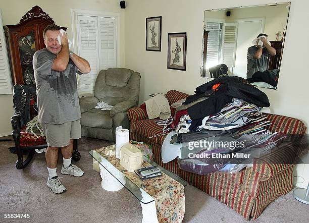 Rusty Toups wipes away sweat as he salvages clothes from the largely unaffected second floor of his home in the Lakeview District October 1, 2005 in...