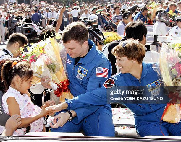 Space Shuttle Discovery commander Eileen Collins of the US, accompanied by US pilot James Kelly, shakes hands with a Japanese girl during a parade in...