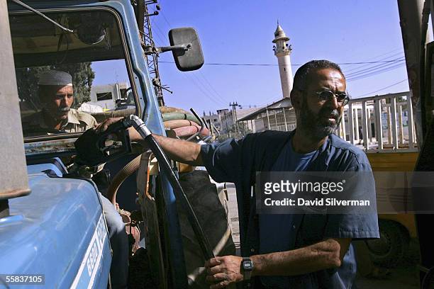 Palestinian gas station attendant Eimad Jallat fills up a Palestinian farmer's tractor with diesel fuel at a gas station October 2, 2005 in Hawarra...