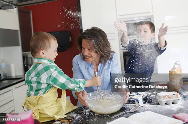 a mom cooking with her 2 boys - kid mess child stock-fotos und bilder