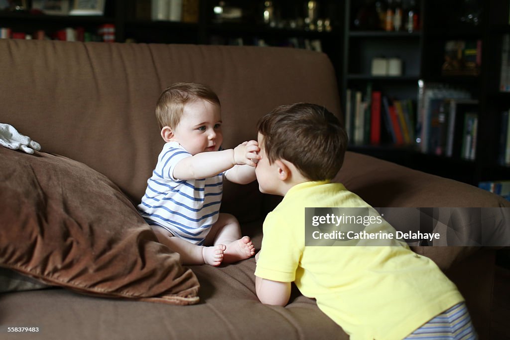 2 brothers playing together on a sofa