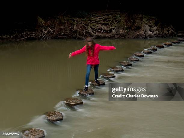 girl in red hops across stone ford on fast river - box hill stock pictures, royalty-free photos & images