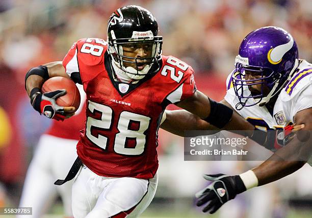 Warrick Dunn of the Atlanta Falcons foists off defensive tackle Spencer Johnson of the Minnesota Vikings in the third quarter on October 2, 2005 at...
