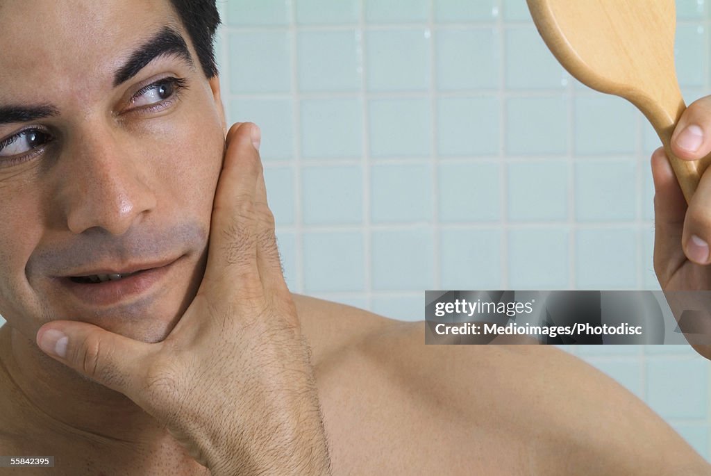 Man looking at himself in vanity mirror, close-up