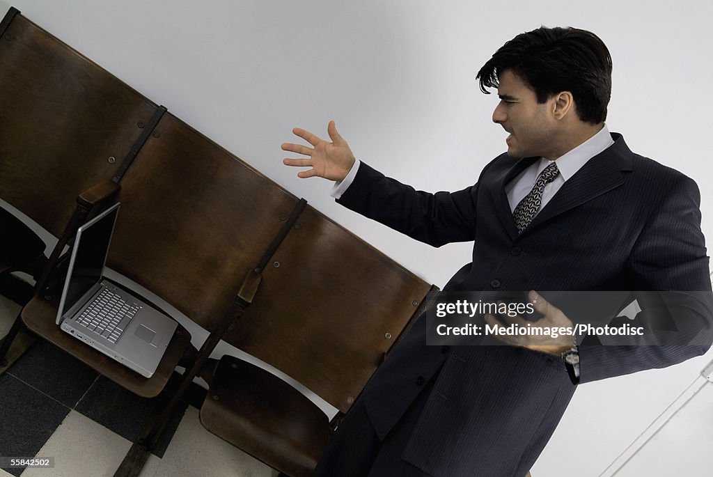 Businessman standing in office upset with computer, tilt