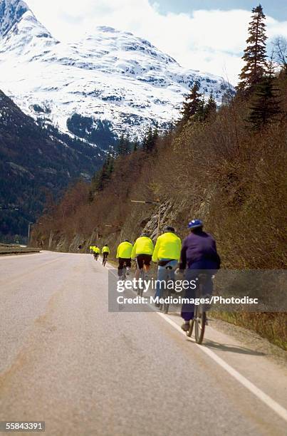 rear view of a group of people cycling on the road, skagway, alaska, usa - skagway stock-fotos und bilder