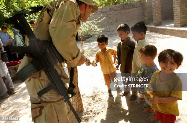 Jalalabad, AFGHANISTAN: A U.S soldier gives candy and cake to children on the outskirts of Jalalabad city in the Nangarhar province east of Kabul, 03...