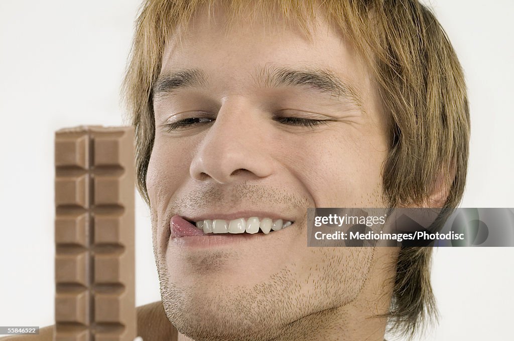 Young man licking his lips and looking at chocolate candy bar