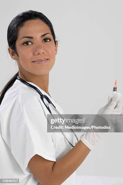 portrait of smiling young female doctor holding syringe - hair back stock pictures, royalty-free photos & images