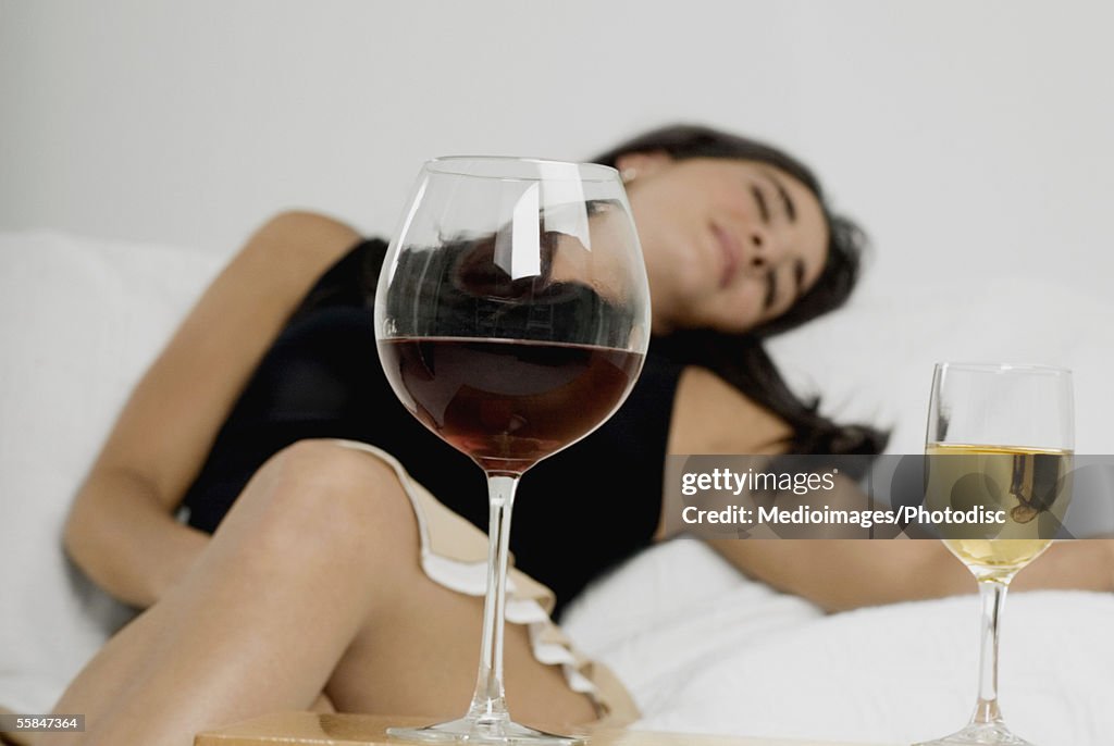 Young woman sleeping with wineglasses in front of her