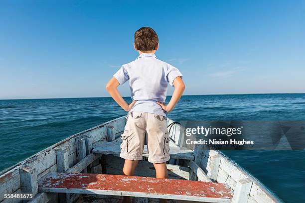 young boy standing in small boat looking out - mujeres hot stock-fotos und bilder