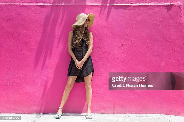 woman with sun hat on leaning against wall - sombrero marrón fotografías e imágenes de stock