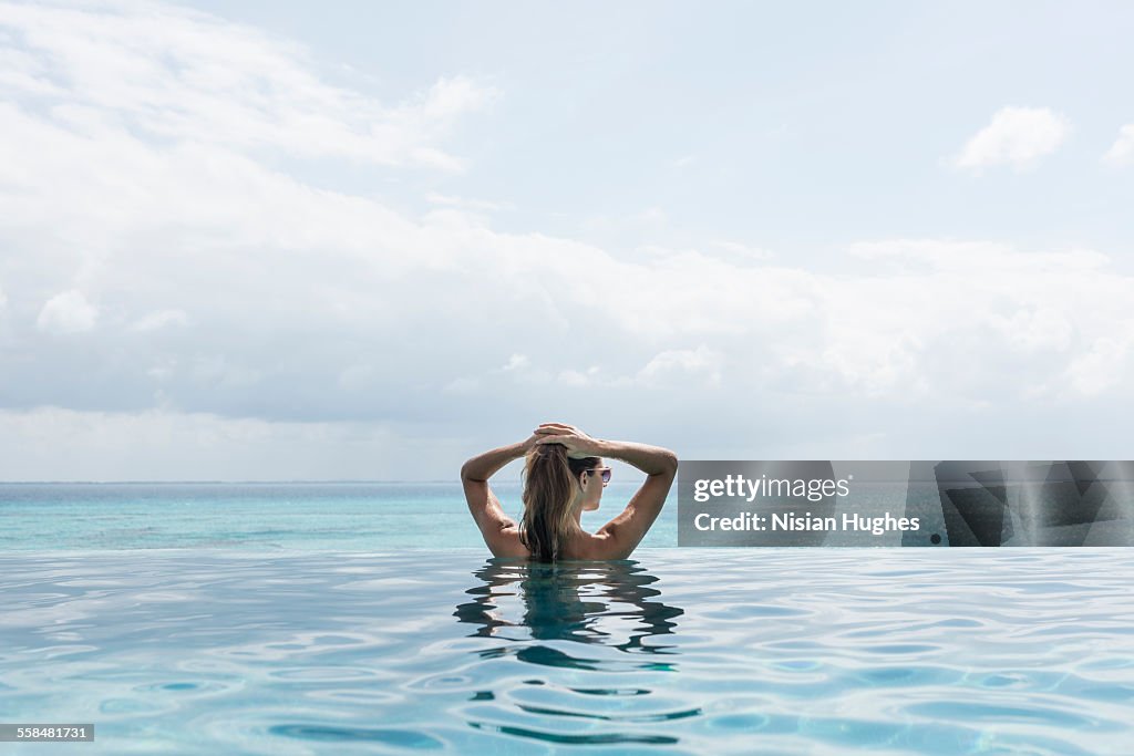 Woman in infinity pool looking out into distance