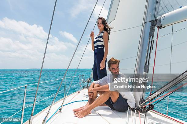 young couple together on sailboat - mujeres hot stock-fotos und bilder