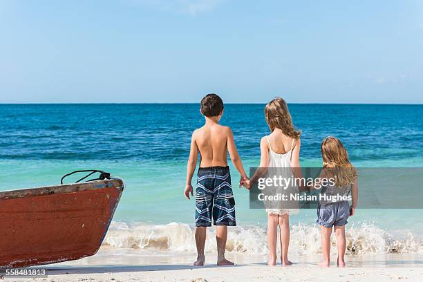 three young kids holding hands back to camera - mujeres hot stock-fotos und bilder