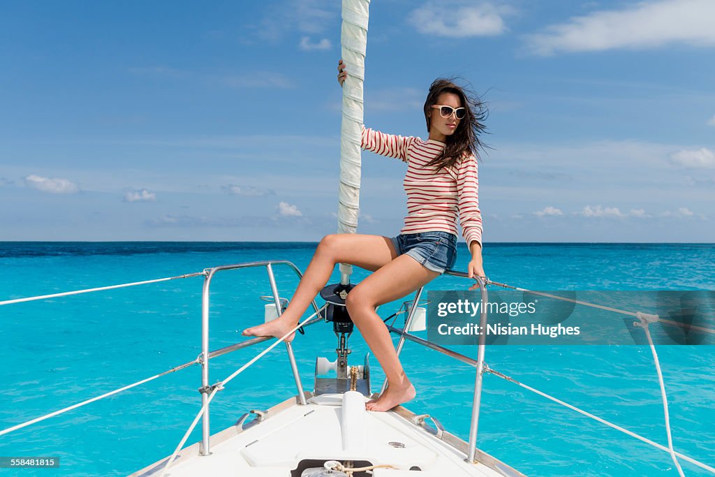 Young woman sitting at the bow of sailboat