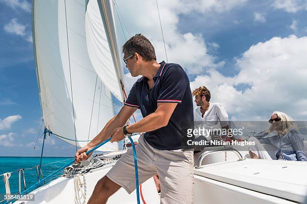 man pulling on rope on sailboat - mujeres hot stock-fotos und bilder