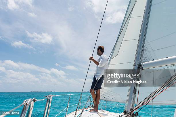 man standing at bow of sailboat looking out - male sailing stock pictures, royalty-free photos & images