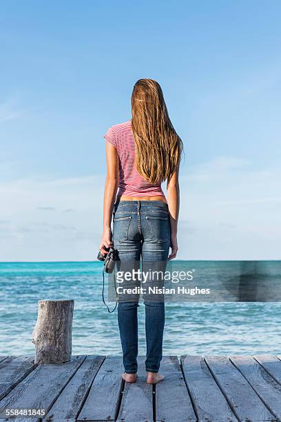 woman standing at end of pier looking out - mujeres latinas stock-fotos und bilder