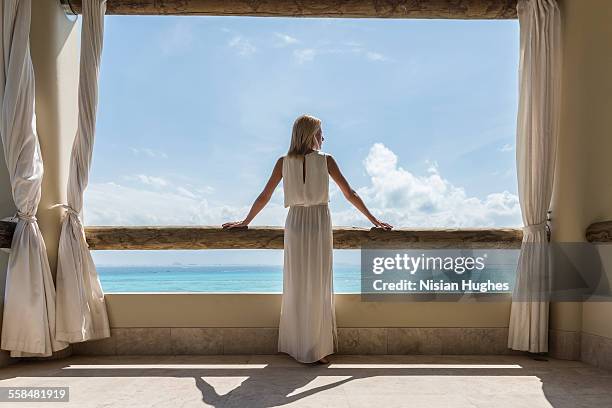 woman on balcony looking out at the ocean - blue dress fotografías e imágenes de stock