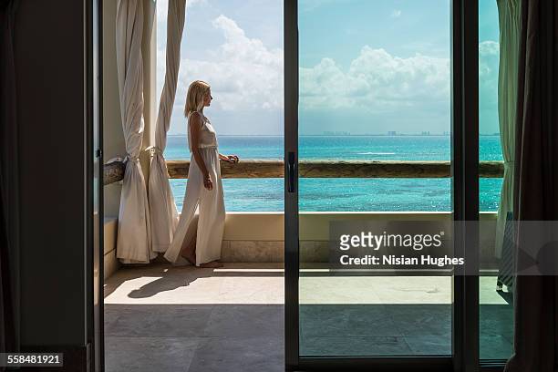 woman standing on balcony overlooking ocean - mujeres hot stock-fotos und bilder