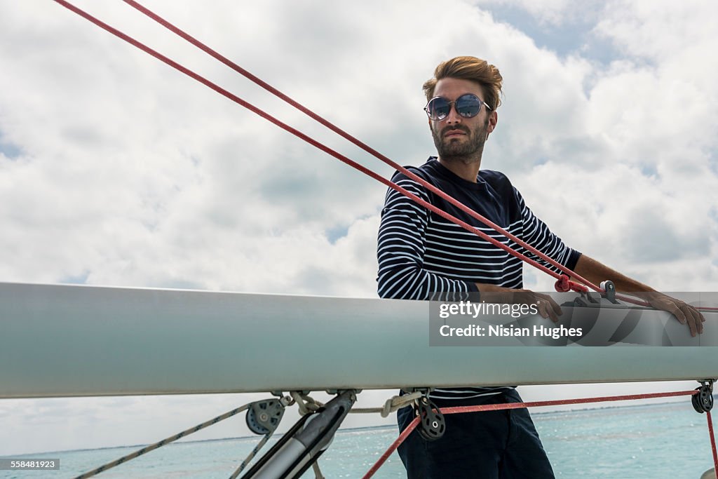 Young man holding boom of sailboat