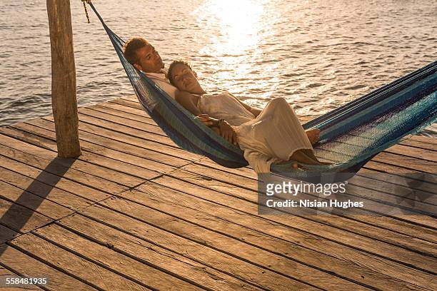 mature couple together in hammock at sunset - mujeres latinas stock-fotos und bilder