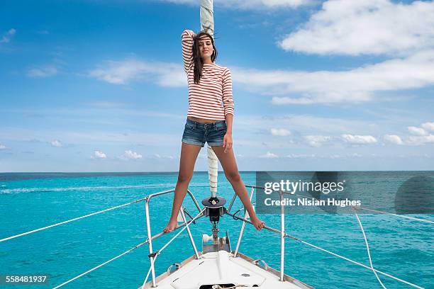 young woman standing at the bow of sailboat - mujeres hot stock-fotos und bilder