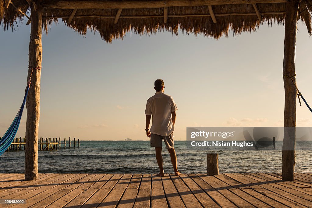 Man at end of pier looking out over ocean