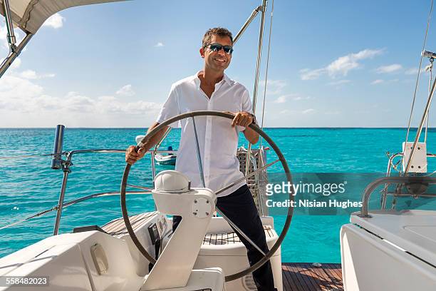 man at the helm steering large sailboat - blue sailboat stock pictures, royalty-free photos & images