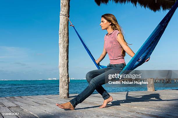 woman sitting in hammock looking out over ocean - mujeres latinas stock-fotos und bilder