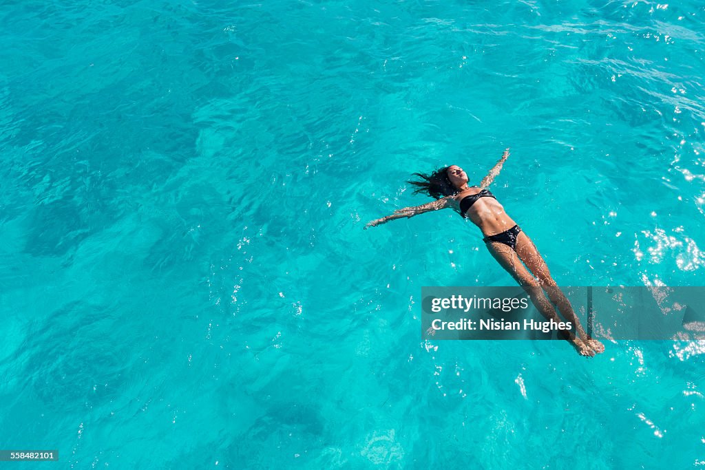 Woman floating on her back, swimming in ocean