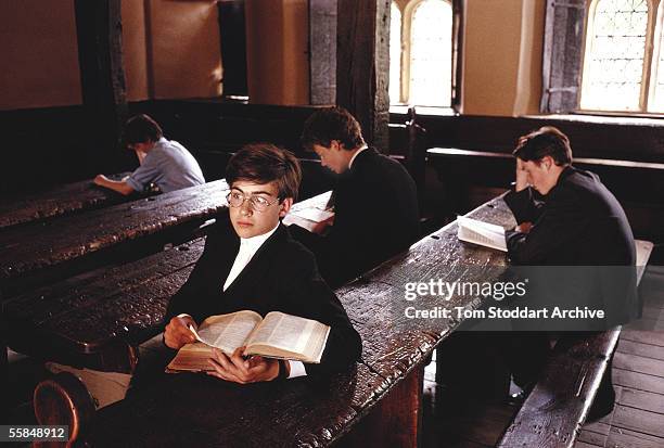Boys from Eton College during a lesson in one of the very old and traditional classrooms which have wooden desks with the names of former pupils...
