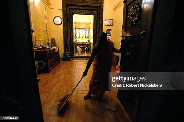 An Indian Buddhist monk sweeps the floor as a crowd of Hindu pilgrims and worshippers gaze at a seated Buddha statue in the Mahabodhi Temple July 24,...