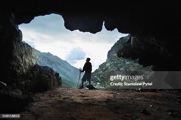 trekking man taking brake in cave - grotta foto e immagini stock