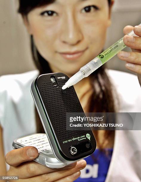 Japanese mobile communication giant KDDI employee displays the prototype model of a mobile phone, produced by Hitachi, powered by a direct methanol...