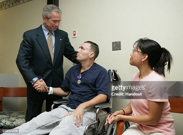 In this handout photo provided by the White House, U.S. President George W. Bush shakes hands with U.S. Army Sfc. Richard Robertson as he presents...