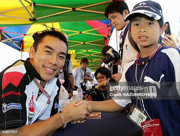 Japanese Formula One driver Takuma Sato of BAR Honda shakes hands with a boy during a signning session of the Japanese Grand Prix at Suzuka circuit...