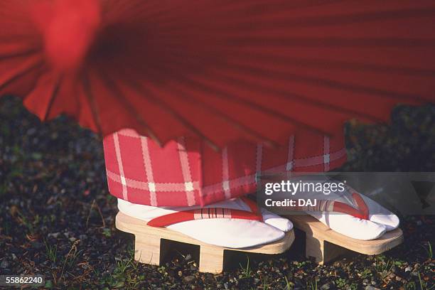 woman putting on wooden clogs - geta sandal stock-fotos und bilder